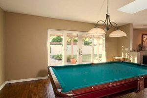 View of family room with wood flooring, pool table, and patio doors leading to backyard.