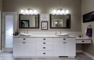 Luxurious bathroom with dual sinks, a pair of vanities, and white cabinetry.