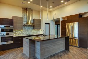 Modern kitchen with wood flooring, minimalistic kitchen island, and stainless steel appliances.