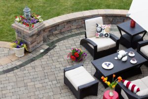 Aerial view of patio space with black outdoor furniture, brick-paved floor, and well-manicured lawn.