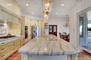 Luxurious kitchen with wood flooring, marble countertops, and an elongated kitchen island.