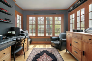 View of home office with wood flooring, wood-frame windows, and charcoal-colored walls.