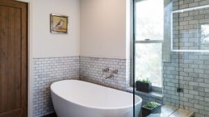 View of newly remodeled bathroom with subway-style tiles on walls, standalone bathtub, and a walk-in shower.