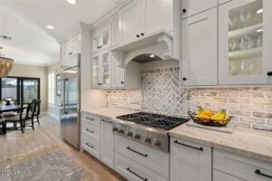 Modern kitchen with white cabinetry, stainless steel appliances, and wood floors.