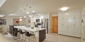 Custom Remodel of a kitchen featuring tile flooring, a kitchen island, and spacious white cabinets.