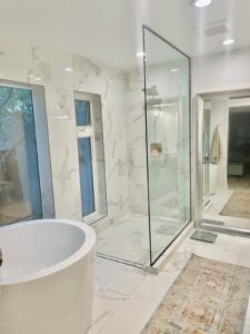 Luxurious bathroom featuring a standalone bathtub, a walk-in shower, and marble flooring and walls.