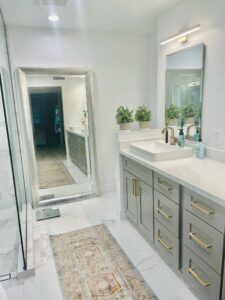 Newly remodeled bathroom with marble floor, large vanity mirror, and updated cabinetry.
